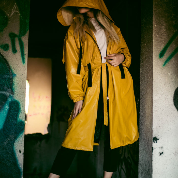a woman in a yellow raincoat standing in a doorway