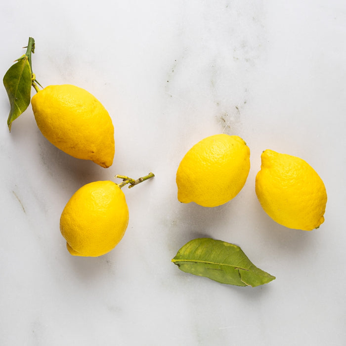 three lemons and three leaves on a marble surface