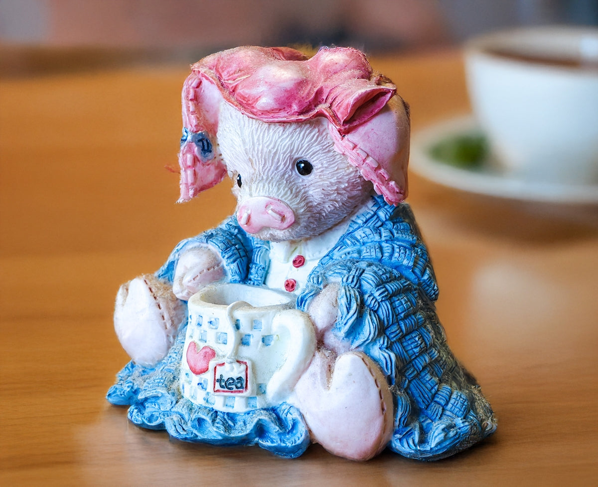 A ceramic pig figurine holding a teacup.