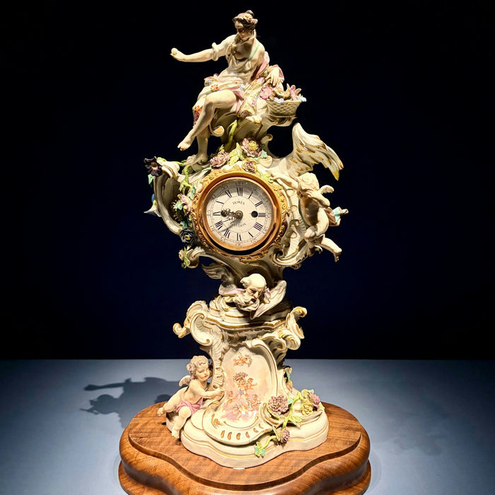 Ornate porcelain mantel clock with cherubs and figures.