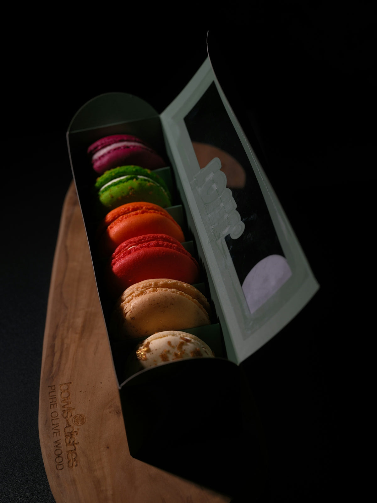 A box of colorful macarons on a wooden board