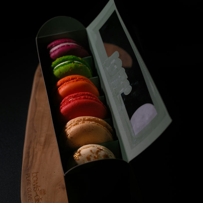 A box of colorful macarons on a wooden board