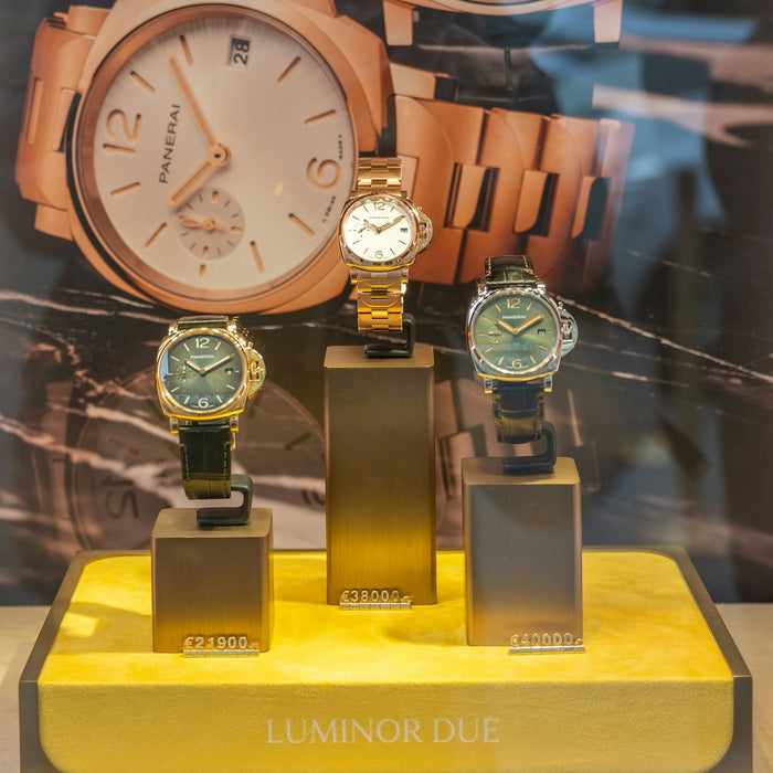 Three luxury watches displayed in a store window