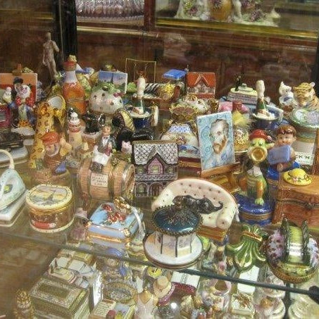 Collection of luxury Limoges boxes for collectors displayed in a glass cabinet showcasing intricate porcelain designs