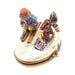 Side view of the crouched skiers on the oval Limoges box, a gift for lovers of the slopes