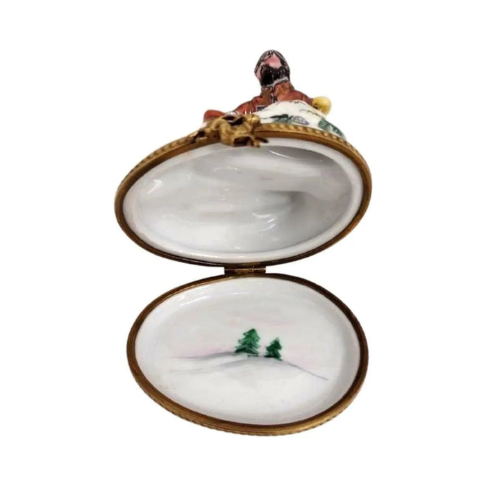 Inside the skiers Limoges box, a snowy slope with a little green fir tree painted on the lid